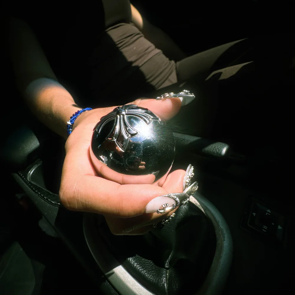 Chrome CROSSED OUT shift knob held inside a car
